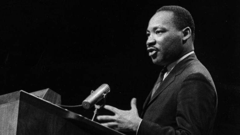 A black and white image of Martin Luther King speaking at a podium